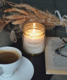 Opsætning på dug med duftlys fra Kathária, tørrede bolomster, kaffekop, bog med briller, Grækenland.