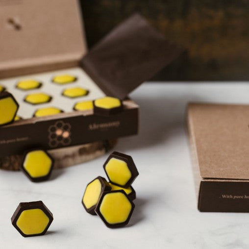 Alemany Chokoladesekskanter med honningfyld – 18 stk i æske på et bord med stykker der ligger på bordet