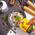 Morganmads bord med en skål med yougurt og mûslie samt en sports sachet fra Miliezia der hældes over